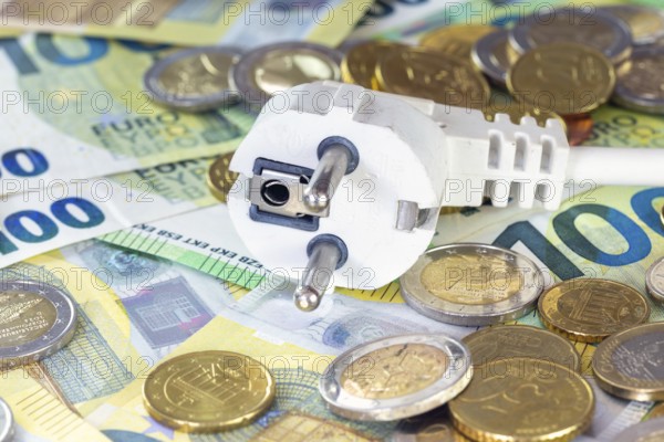 Symbolic image of electricity costs: power plug with euro banknotes and euro coins