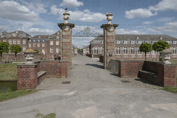 Large brick building with Tor tor and decorated pillars under a blue sky, moated castle Nordkirchen, MÃ¼nsterland, North Rhine-Westphalia, Germany