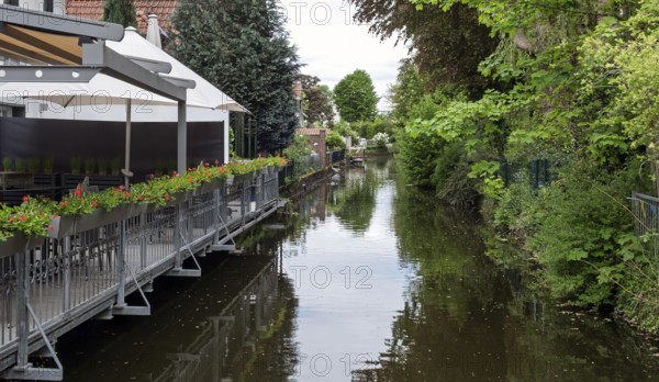 River with adjoining terrace and flowers, surrounded by green vegetation, Borken-Gemen, MÃ¼nsterland, North Rhine-Westphalia, Germany