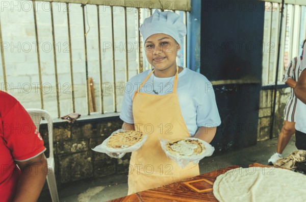 Portrait of a vendor serving and holding two pupusas. Smiling female vendor holding two plates of traditional pupusas