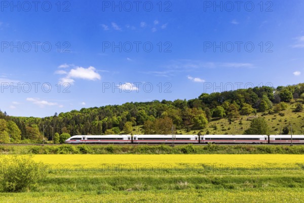 InterCityExpress ICE en route on the Swabian Alb near Lonsee. Landscape on the railway's Filstalline line in spring with rape fields in bloom. Lonsee, Baden-WÃ¼rttemberg, Germany