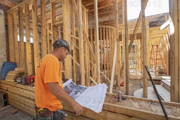 Detroit, Michigan - Jay Newcomb III looks over architectural plans as workers rehab a long-vacant and crumbling commercial building in the Morningside neighborhood. The project, called Ultreia, will contain first floor commercial space and apartments above