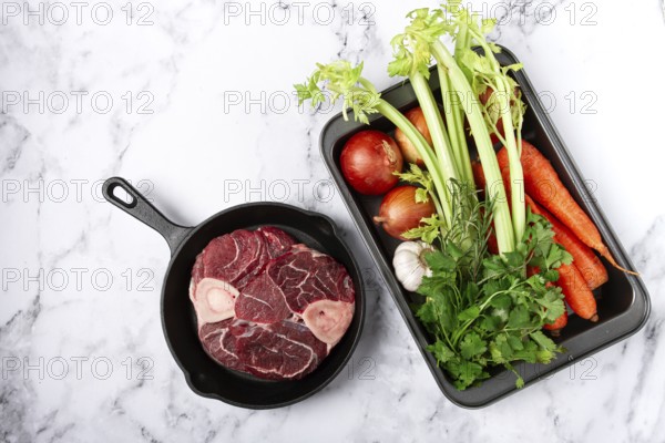 Sknuckle on the bone, raw meat for ossobuco, in a cast-iron pan, baking sheet with vegetables, top view, no people