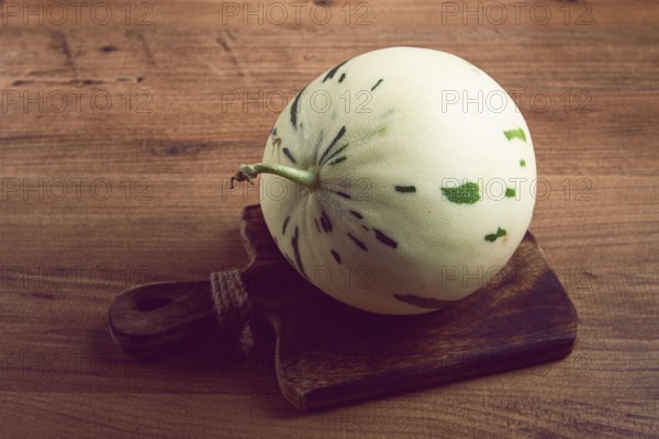 Dino melon, white with green stripes, small size, on the table, close-up, no people