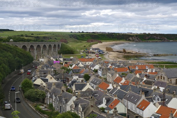 Coastal town with a viaduct and orange tiled roofs under a cloudy sky, Portsoy, Aberdeenshire, Scotland, United Kingdom