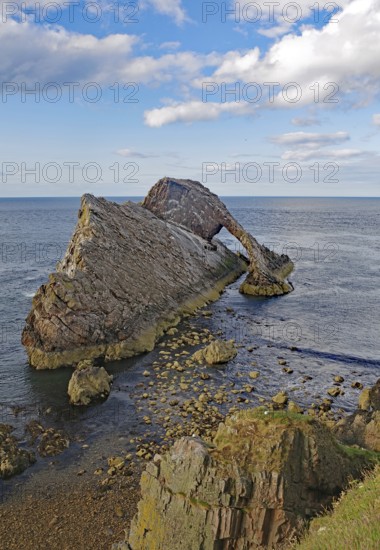 Remarkable rock formation jutting into the sea under a blue sky with few clouds, Bow Fiddle Rock, Aberdeenshire, Buckie, Scotland, United Kingdom