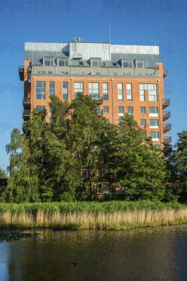Newly (2025) built apartment building rising above the trees and behind a pond in Ystad, SkÃ¥ne County, Sweden, Scandinavia