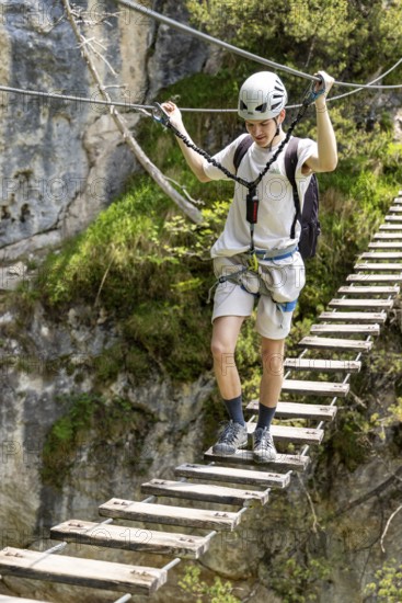 Mountaineer climbing over a suspension bridge on the Isidor via ferrata, GrÃ¼nstein, Schönau am Königssee, Berchtesgadener Land, Upper Bavaria, Bavaria, Germany