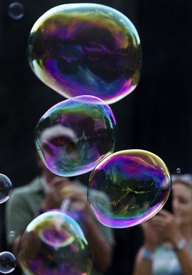 A man and a woman photograph iridescent soap bubbles in front of a black background, Recklinghausen, North Rhine-Westphalia, Germany