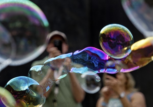 A man and a woman photograph iridescent soap bubbles in front of a black background, Recklinghausen, North Rhine-Westphalia, Germany
