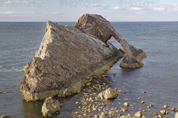 A large rock with a natural arch by the sea, surrounded by water, Bow Fiddle Rock, Aberdeenshire, Buckie, Scotland, United Kingdom