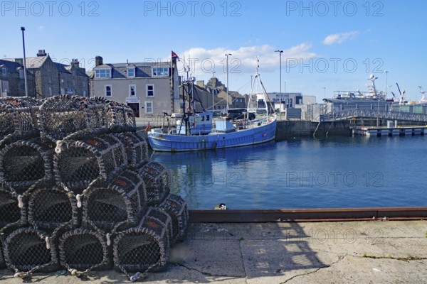 A harbour with fishing boats and stacked nets under a clear sky, Fraserburgh Aberdeenshire, Scotland, United Kingdom