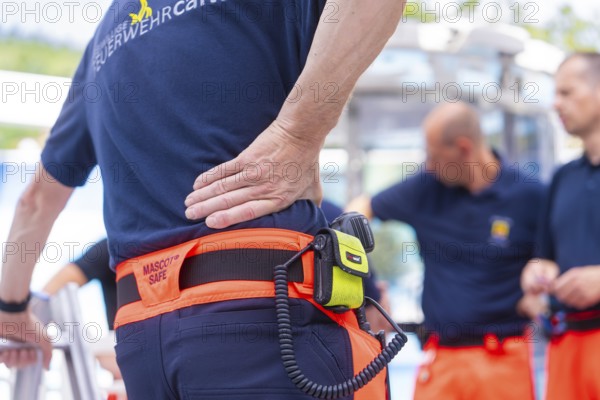 Firefighters in uniform talk to each other, one wears a radio on his belt, fire brigade exercise for gondola rescue, Germany