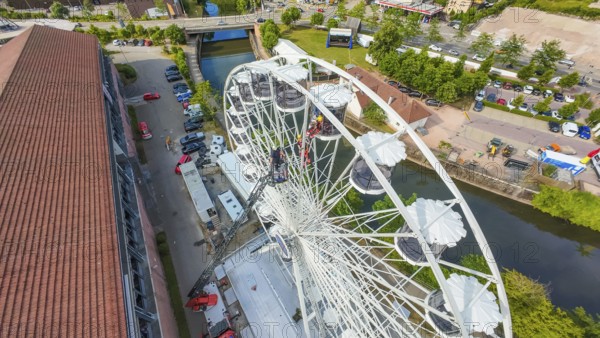 View from above of a Ferris wheel next to a river and buildings, fire brigade exercise for gondola rescue, Germany