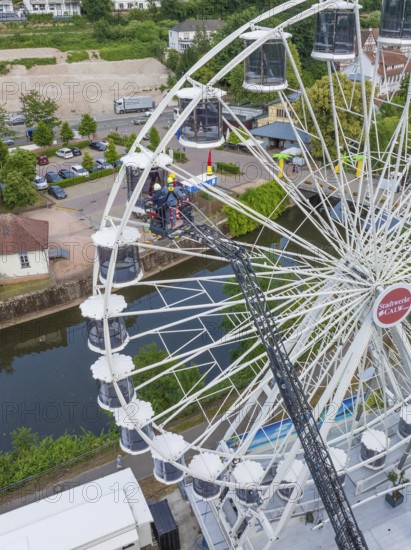 Workers working on a Ferris wheel near a river and building, fire brigade exercise for gondola rescue, Germany