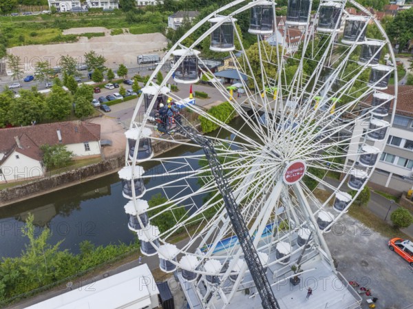 Aerial view of a Ferris wheel next to a river with cars on the road and trees in the background, fire brigade exercise for gondola rescue, Germany