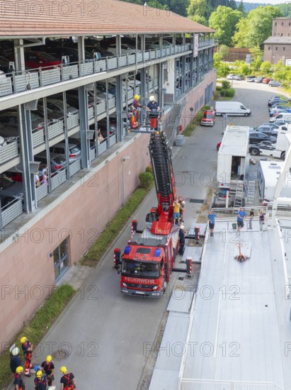 Fire engine and workers at a building with a lifting platform in an urban environment, fire brigade exercise for gondola rescue, Germany