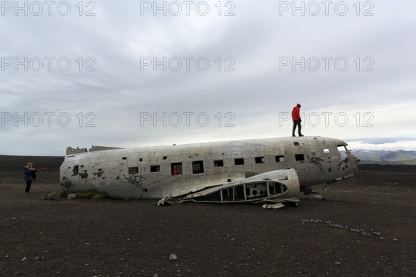 Tourist on aircraft wreckage, US Navy Douglas DC-3 transport plane, Sander, volcanic landscape, SÃ³lheimasandur, Solheimasandur, near ring road, SuÃ°urland, Sudurland, South Iceland, Iceland