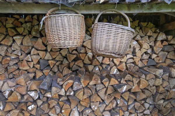 Two baskets hanging in front of a pile of wood, Germany