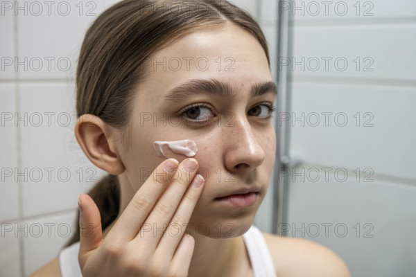 Teenager applying skin cream in bathroom. Honest daily skincare and self-care routine. Generative ai, AI generated