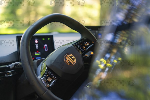 Close-up of the steering wheel and the screens in the car, trees and light in the background, MG 4, Deer E- Car Sharing, district of Calw, Germany