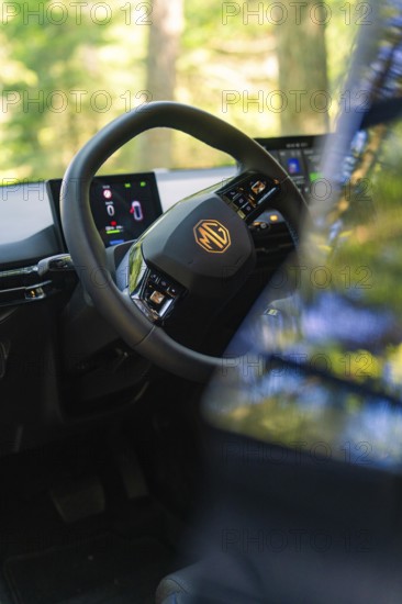 Interior of a car with focus on the steering wheel and digital displays, background of trees, MG 4, Deer E- Car Sharing, district of Calw, Germany