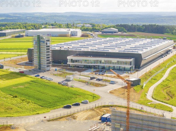 Large modern warehouse in the middle of green fields under a cloudy sky, industrial area, Nagold, I district of Calw, Germany