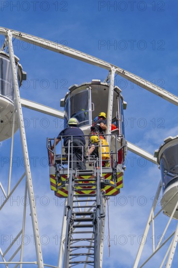 Rescue workers help a person in a giant wheel cabin, fire brigade exercise for gondola rescue, Germany