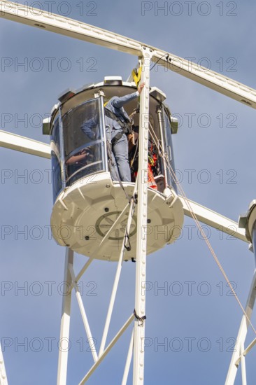 Workers in a cabin of a Ferris wheel carrying out maintenance work, fire brigade exercise for gondola rescue, Germany