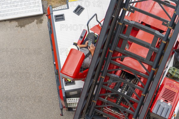 A firefighter operates the controls of a large mobile crane, fire brigade exercise for gondola rescue, Germany