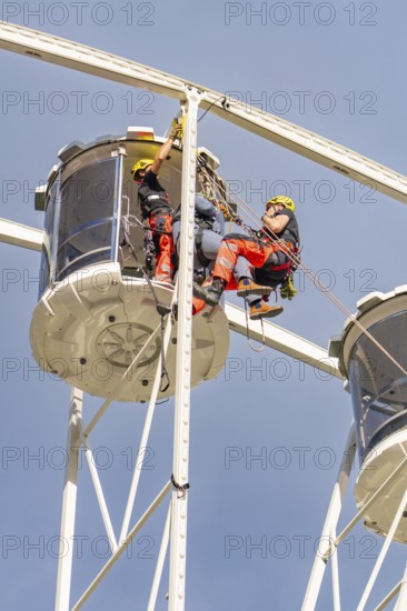 Two workers in protective clothing carry out inspections on a Ferris wheel, fire brigade exercise for gondola rescue, Germany