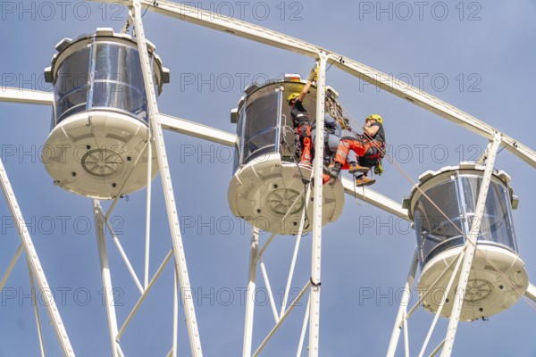 Two workers in equipment working on the structure of a Ferris wheel, fire brigade exercise for gondola rescue, Germany