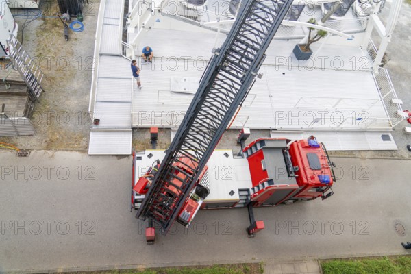 A large fire engine with crane boom is parked on a road, fire brigade exercise for gondola rescue, Germany