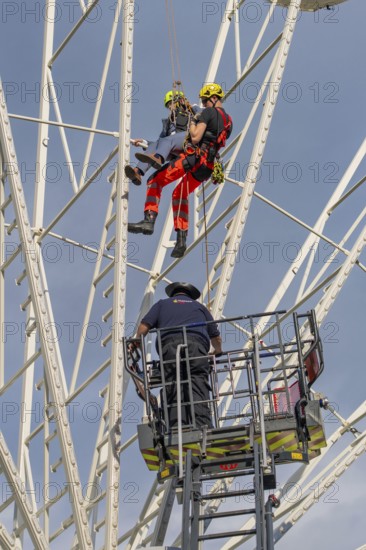 Firefighters on a rescue mission on a Ferris wheel with crane support, fire brigade exercise for gondola rescue, Germany