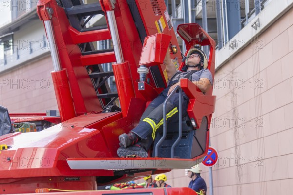 Firefighter relaxing on a lifting platform near a building, fire brigade exercise for gondola rescue, Germany
