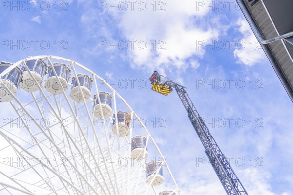 Lifting platform reaches the top of the Ferris wheel in a clear sky, fire brigade exercise for gondola rescue, Germany