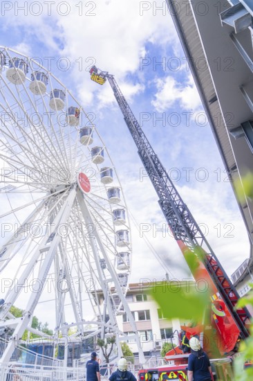 Rescue workers on a lifting platform next to a Ferris wheel in good weather, fire brigade exercise for gondola rescue, Germany