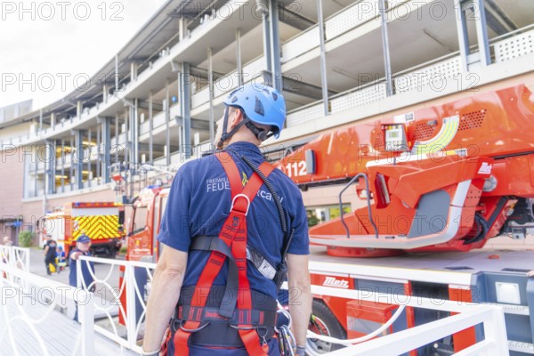 Fire brigade employee with protective helmet looking at a red fire engine, fire brigade exercise for gondola rescue, Germany