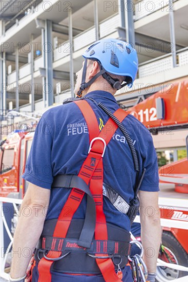 Fire brigade employee with safety equipment looking at a vehicle, fire brigade exercise for gondola rescue, Germany
