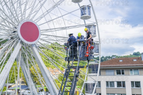 Firefighters carry out rescue operation on a Ferris wheel in a city, fire brigade exercise for gondola rescue, Germany