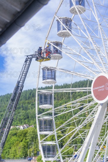 Firefighters carry out a rescue operation in a Ferris wheel standing in a green environment, Fire brigade exercise for gondola rescue Ferris wheel, Calw, Germany