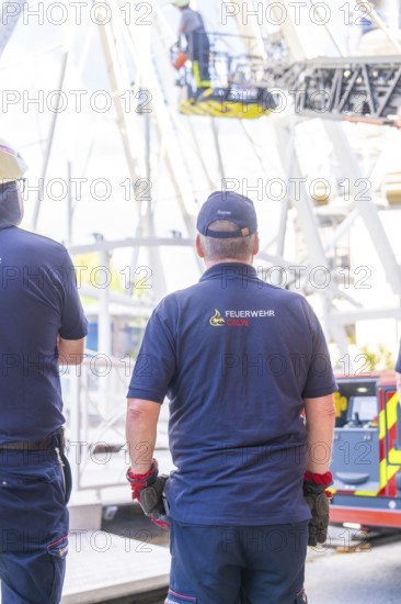 Firefighters stand ready in uniform while a rescue operation takes place on the Ferris wheel, Fire brigade exercise for gondola rescue Ferris wheel, Calw, Germany
