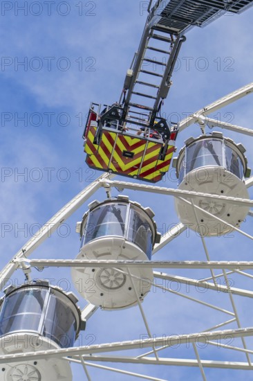 Rescue ladder of the fire engine reaches the cabins of the Ferris wheel, background with blue sky, fire brigade exercise for gondola rescue Ferris wheel, Calw, Germany
