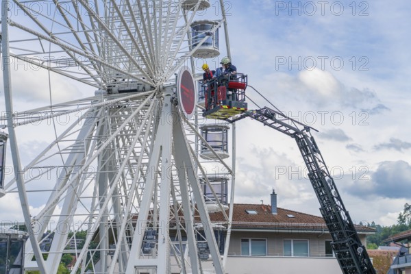 Firefighters during rescue work on a Ferris wheel with residential buildings in the background, Fire brigade exercise for gondola rescue Ferris wheel, Calw, Germany