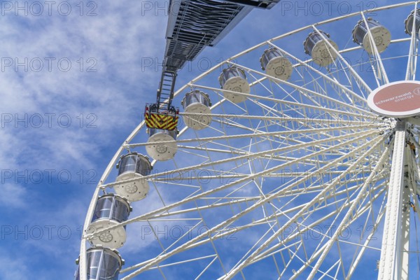 A fire brigade ladder extends to the Ferris wheel, which rises against the blue sky, Fire brigade exercise for gondola rescue Ferris wheel, Calw, Germany