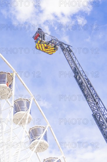 Zoom on fire brigade ladder close to the Ferris wheel in front of blue sky, fire brigade exercise for gondola rescue Ferris wheel, Calw, Germany