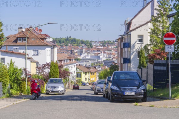Urban street with cars, a no cycling sign, a scooter and a backdrop of houses under a clear sky, Pforzheim, Germany