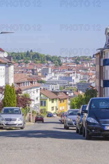 View of a city street with parked cars and background buildings under a blue sky, Pforzheim, Germany