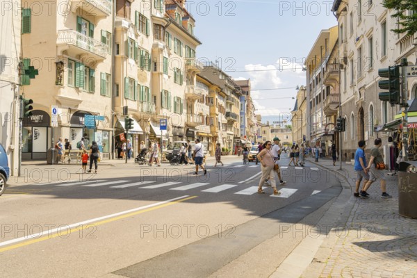 Lively street in the city centre with pedestrians and historic buildings in sunny weather, Merano, South Tyrol, Italy