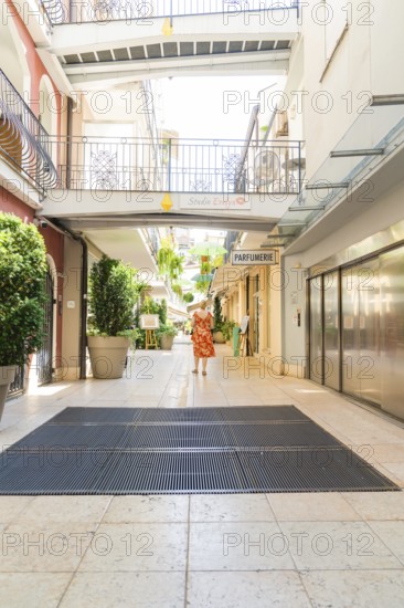 Courtyard passage with smiling woman and hanging plants, Merano, South Tyrol, Italy
